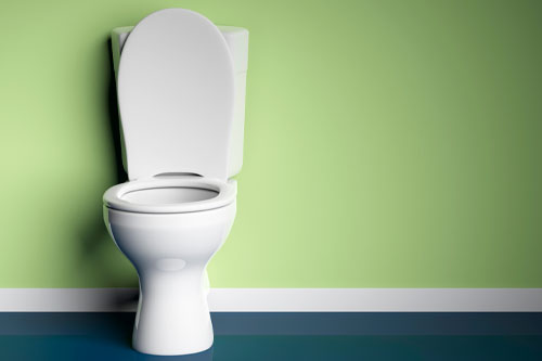 Image of a toilet with the lid open in front of a green wall