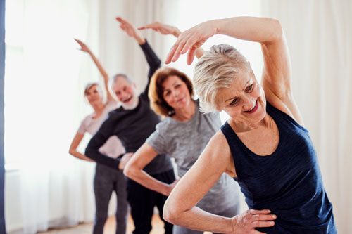 group of older adults stretching overhead